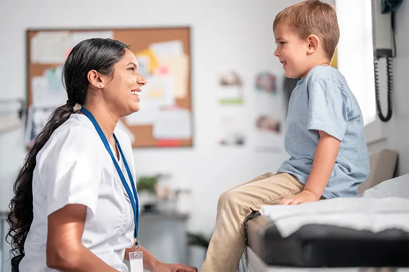 Female doctor and a young boy sharing a laugh in a treatment room