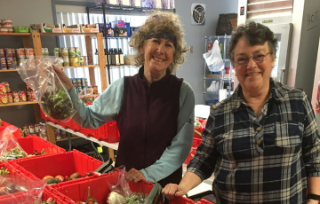 two women sorting groceries smiling