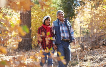 Senior female and male walking through a forest in autumn